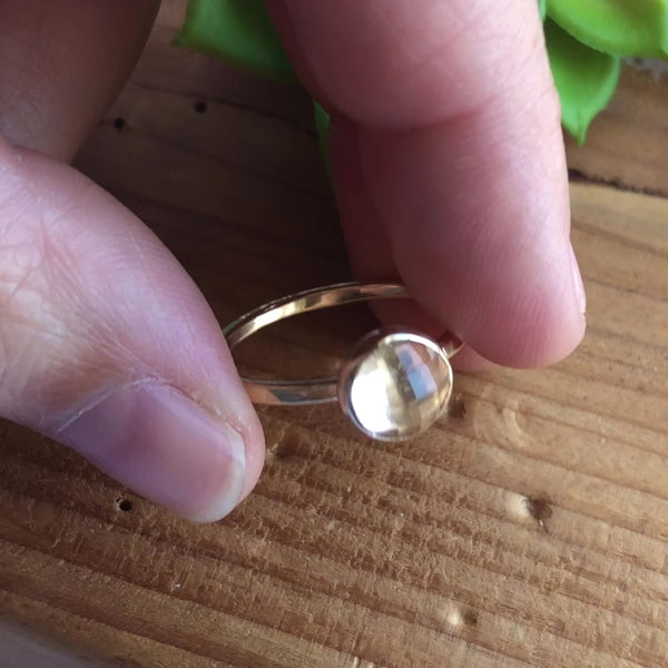 A large 8mm sparkling white topaz stone that is rose cut is set in a gold bezel setting and set onto a hammered textured golden band.  The band is narrow for comfort fit and can be stacked with other rings.
